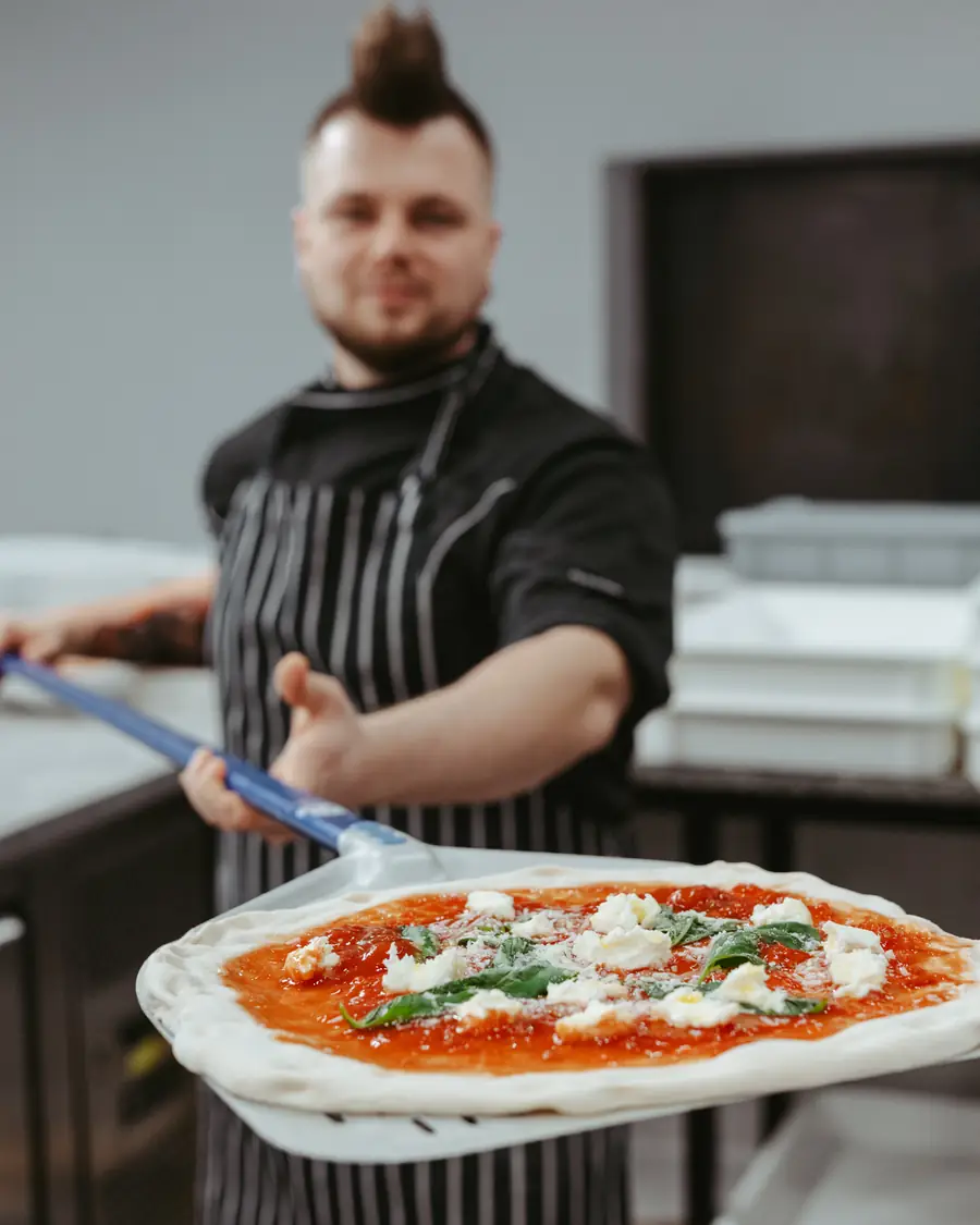 Pizzaiolo z łopatą i świeżo upieczoną pizzą