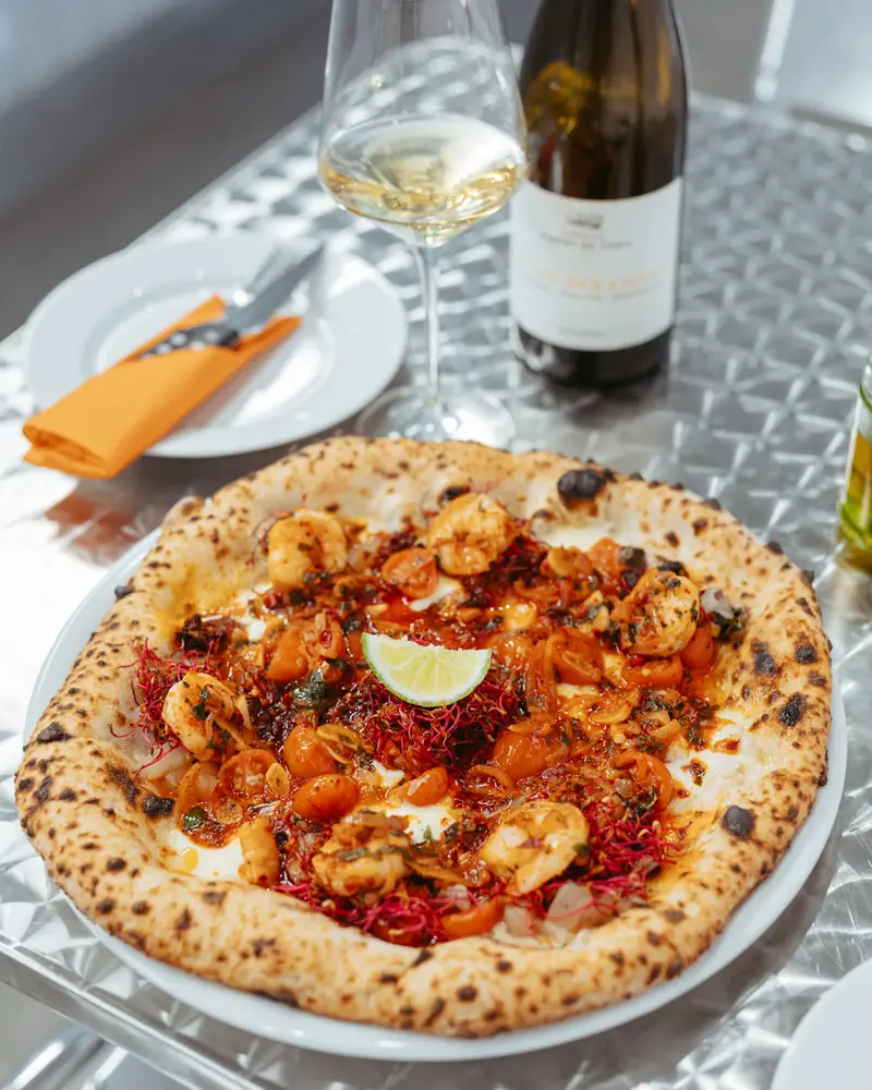 Pizza i butelka białego wina na stoliku